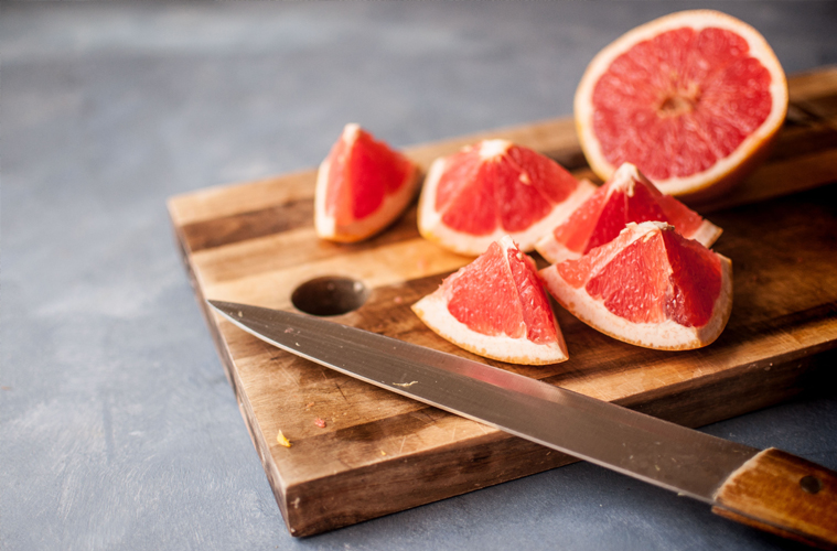 knife and grapefruit cut on a wooden board